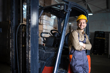 Portrait of warehouse forklift driver standing in storehouse by the machine. © littlewolf1989