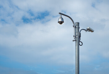 360 Degree fish eye dome CCTV and CCTV camera are installed on column against blue sky.