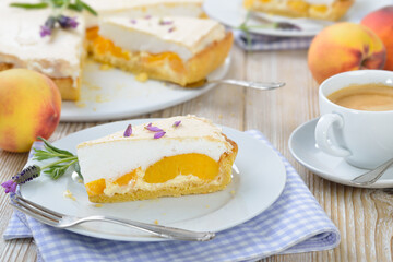 Leckerer Pfirsich-Tarte mit Lavendelhonig und Baiserhaube sowie einem Cafe Creme auf einem Holztisch  mit Deko - Peach pie with lavender honey topped with sweet meringue served  with a cup of coffee