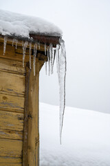 large icicle on the roof of a wooden rural house, village