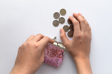 open pink wallet with scattered coins and hands on a white background