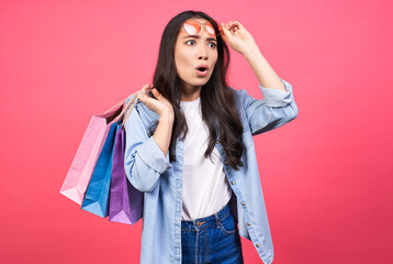 Image of a beautiful shocked young woman holding shopping bags.