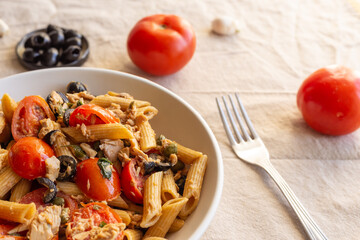 Penne pasta with tuna, capers, tomato and black olives. Typical italian dish.