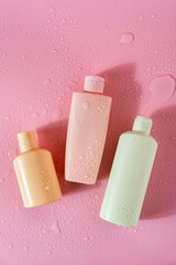 Cosmetic products with water drops on pink backgroundr. Space for text. Flat lay composition