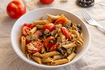 Penne pasta with tuna, capers, tomato and black olives. Typical italian dish.