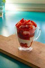 Yogurt glass with strawberries, on a wooden background. Summer snack, healthy snack.