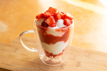 Yogurt glass with strawberries, on a wooden background. Summer snack, healthy snack.