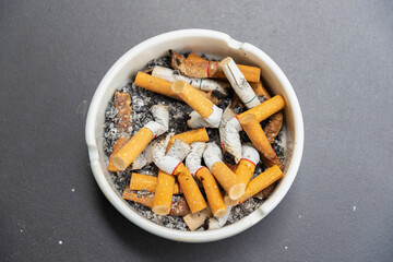 Cigarette stub in the ashtray on the table. Center position. ฺBad health, danger.