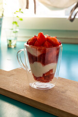 Yogurt glass with strawberries, on a wooden background. Summer snack, healthy snack.