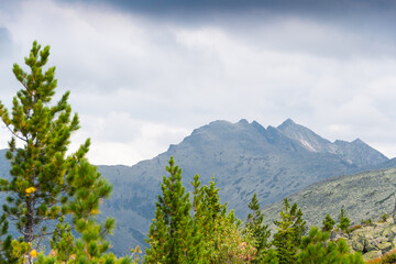 Panoramic view of rocky ridge. Mountains on horizon under cloudy sky. Travel through mountain valley on sunny day.