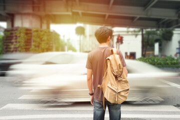 Defocus Back of Young male traveler traveling backpacker beside road with Blurry car on the way...
