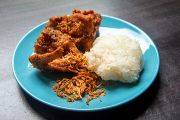 Top view Fried chicken and fried onion with sticky rice in the light blue dish on brown wooden. fried chicken the most famous food of Hat-yai Songkhla Thailand. Culture food. Fat food.