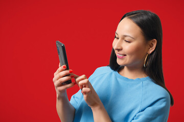 Young woman using a smartphone on red