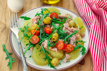 Potato salad with tuna, cherry tomatoes, olives and arugula