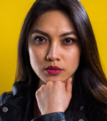 Portrait shot of a young self-confident woman against yellow background - studio photography