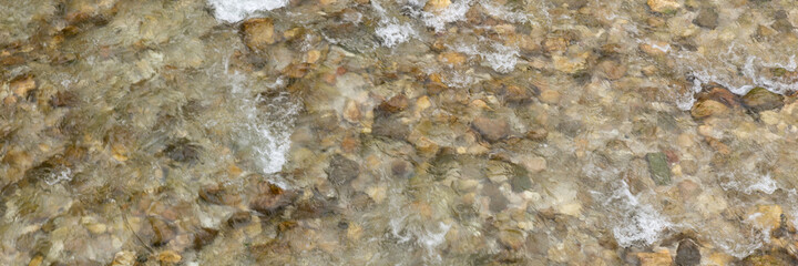 Nature background with many stones on bottom of river with clear water. Panoramic image