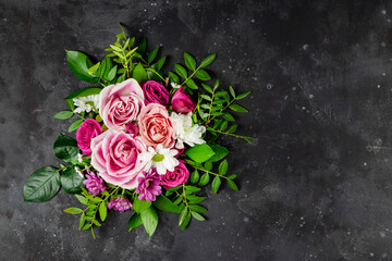 Fototapeta na wymiar Composition of delicate summer flowers on a black background top view, free space for text. Bouquet of pink roses and white daisies