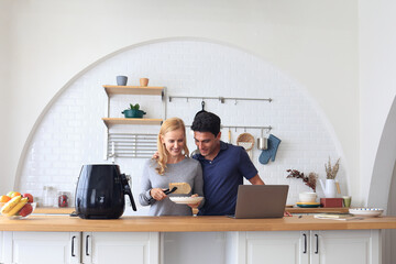 The Caucasian family Make breakfast with the air fryer together. Husband and wife Cooking in the...