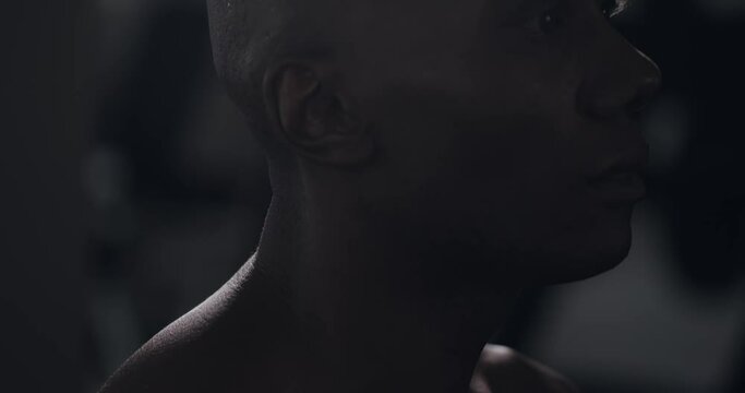 Handsome black man lifts head resolute in dark, Closeup on neck and head