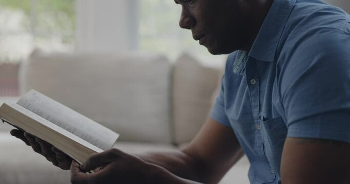 Mature Black Man Reading Bible in Living Room, Pan from Face Down to Book