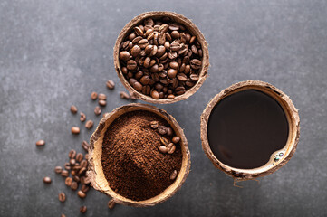 stages of preparation of black coffee, beans, ground, freshly brewed in coconut bowls, view from above
