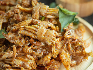Fried crab and herb on wooden dish and black wood background. Thai and spicy food. Selective focus.