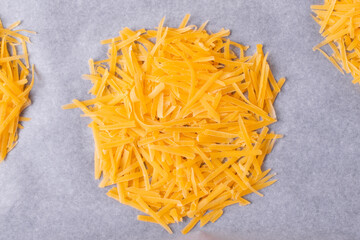 Cooking Cheddar cheese chips. Grated cheese shaped into circle on the oven tray