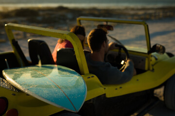 Caucasian couple sitting in beach buggy by the sea talking