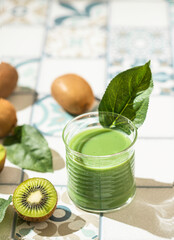 Healthy green smoothie from kiwi and tile background. Smoothie with sunshine and hard shadow.