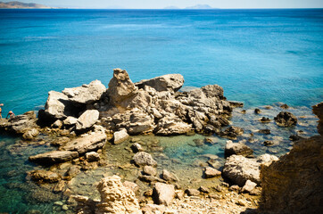 Fototapeta na wymiar Strange Shape Rocks on the Seashore in Preveli Beach at Greek Island Crete, Greece. Swimmers Dive into the Beautiful Blue Colored Waters.