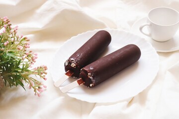 Two chocolate vanilla flavor ice cream with stick and cup of coffee. Delicious summer dessert, flat lay composition food photography, view from above