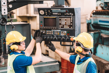 Work at factory.Asian worker man  working in safety work wear with yellow helmet and ear muff using equipment.in factory workshop industry machine professional