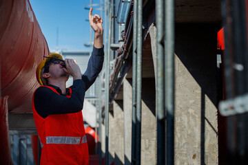 Confident supervisor using walkie-talkie at construction site construction. engineer on plant....