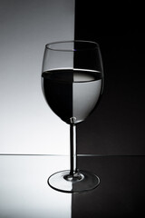 Glass for wine on a half black half white background