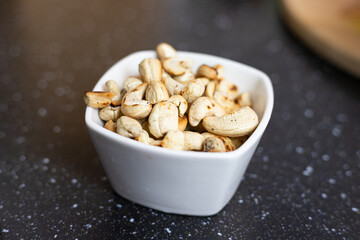 Roasted cashews in a white bowl. Preparation of the meal.