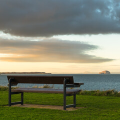 Fototapeta na wymiar bench at sunset looking out to the Bass Rock