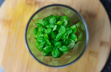 Basil leaves thrown into a blender. Prepare basil pesto.
