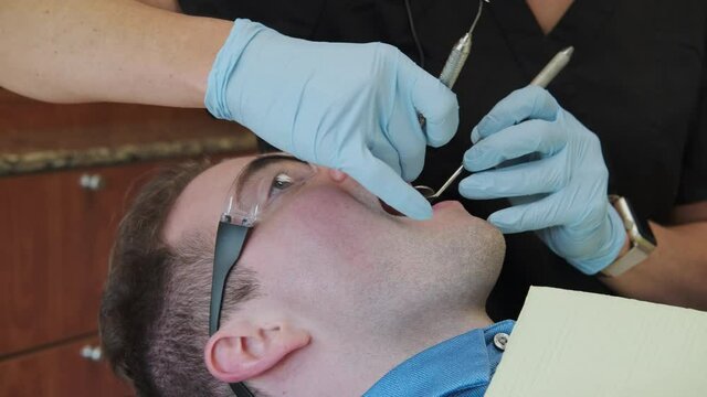 Close Up Slow Pan Dental Hygienist Hands Examining the Teeth of a Caucasian Man
