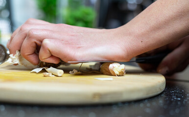 A person crushing garlic with a knife. Preparation of the meal.