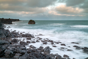 Fototapeta na wymiar The waves of the Atlantic ocean beat against the rocky bareg of Iceland. long exposure time