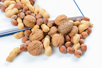 Blend of nuts with open notepad and white sheets. Food caloric record concept. Accounting for healthy nutrition.