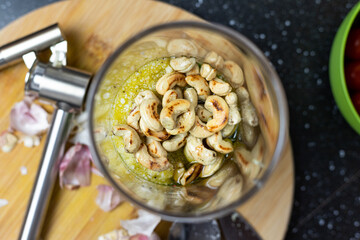 Ingredients for basil pesto in a blending container. Visible cashews. View from above.