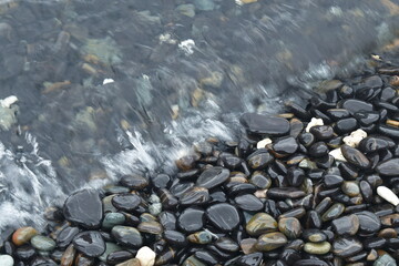 sea wave flowing to black rock on beach from Lipe island travel location in Thailand