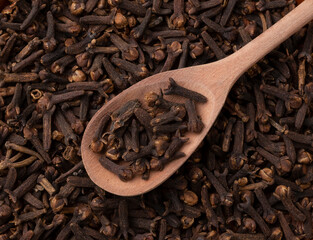 Top view, closeup of cloves on a wooden spoon. Food backdrop