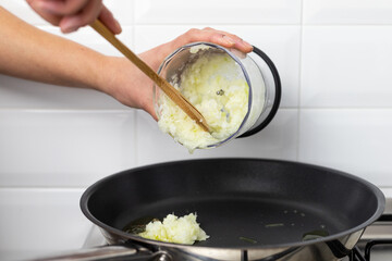 A person throwing chopped onions into the pan. Preparation of the meal.