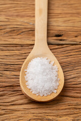 Closeup of coarse salt on a wooden spoon. Food backdrop