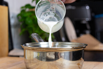 Pouring milk into a pot. Preparation of béchamel sauce.