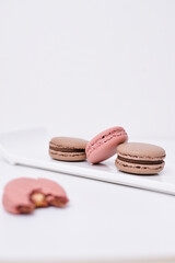 Obraz na płótnie Canvas four pink and brown macaroons standing on the white plate, copy space