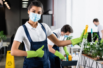 African american worker of cleaning company with mop showing like sign in office