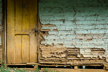 pared vieja con puerta amarilla y ladrillo gastados de color azul, casa de barro de color azul